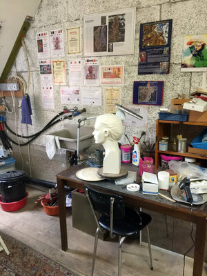 Manuella Muerner Marioni in de studio: Mein Atelier, wo die Skulpturen entstehen. Man sieht ein Männerprofil, das noch in der Roharbeit ist.