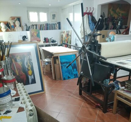 Jenifer Carey en el estudio: Es una fotografía de mi estudio. En primer plano se ve el tórculo para estampar grabados. En el fondo se ve muchas obras  y una de las mesas de trabajo.