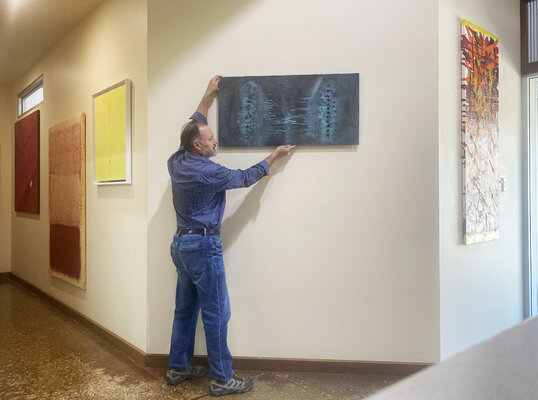 Malcolm Koch in de studio: Arranging artwork on exhibit in the studio gallery
