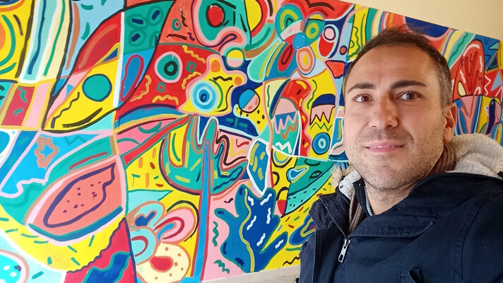 Rosario Annunziata im Studio: Il murales è stato realizzato in collaborazione con istituzioni pubbliche per promuovere l'inclusione . Si vede il dettaglio della stampa sulla t-shirt