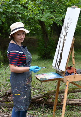 Lilit Vardanyan nello studio: This photo captures me painting plein air, fully immersed in nature. Working outdoors allows me to observe trees directly, feel the atmosphere around me, and translate that quiet connection with nature onto the canvas through spontaneous, living brus