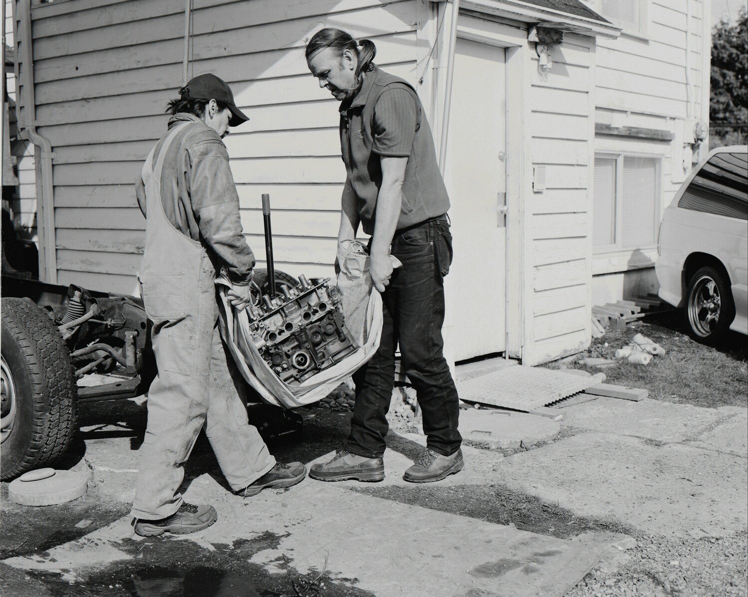 Men move an engine block Jeff Wall Fotografia in vendita