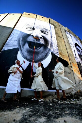 28 Millimètres: Face 2 Face, NUNS IN ACTION, SEPARATION WALL; SECURITY FENCE, PALESTINIAN SIDE, BETHLEHEM di JR, Fotografia in vendita su Singulart