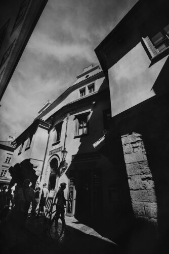 A street view in Prague, human silhouettes and classical architecture . B&W . di ihsan Okur, Digitale in vendita su Singulart