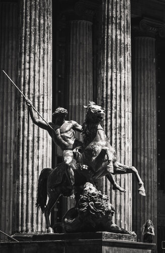 (Löwenkämpfer) The lion fighters statue, columns in the background and a woman in the corner entering the frame. by ihsan Okur, Photography for Sale on Singulart