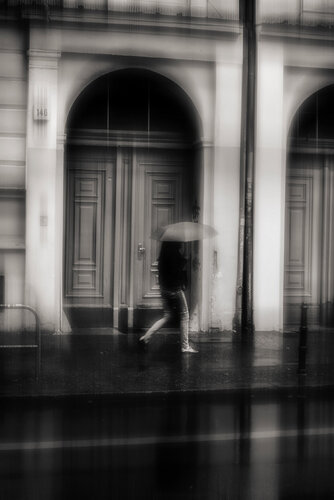 A girl with umbrella on a rainy day and local architectural details in the background in Berlin. di ihsan Okur, Fotografia in vendita su Singulart