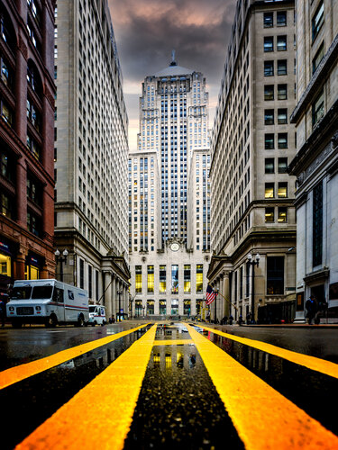 Chicago Board of Trade Building towering over rain soaked financial district street by Lev Kaytsner, Photography for Sale on Singulart